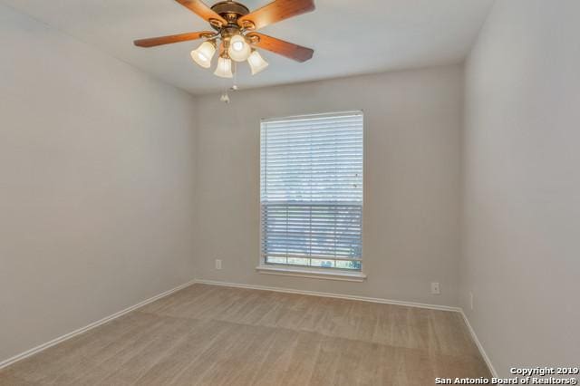 empty room featuring a ceiling fan, light carpet, and baseboards