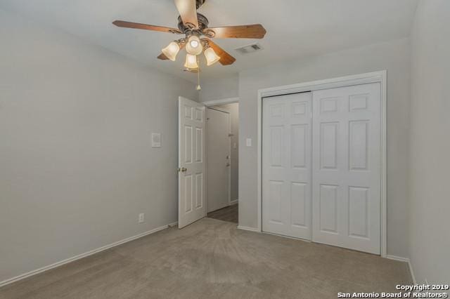 unfurnished bedroom featuring a closet, light colored carpet, visible vents, a ceiling fan, and baseboards
