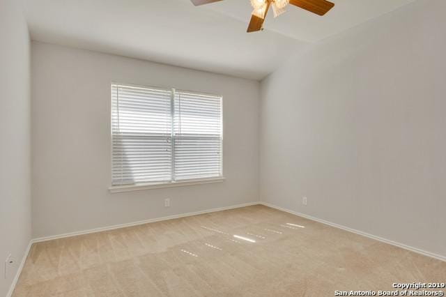 unfurnished room with light carpet, ceiling fan, vaulted ceiling, and baseboards
