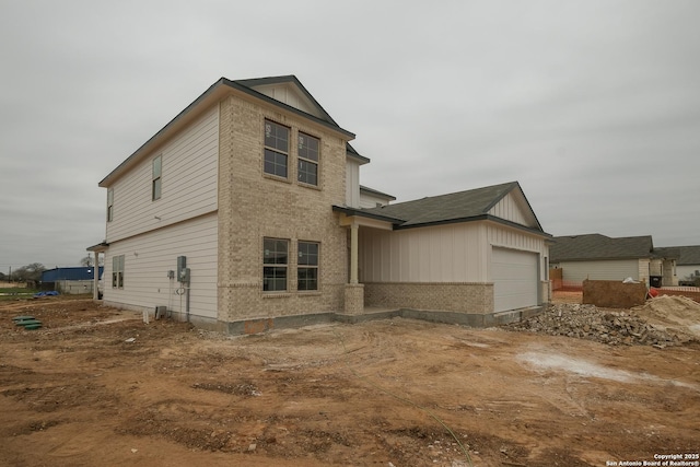 view of front facade featuring a garage, brick siding, and board and batten siding