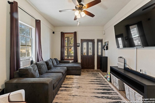 living area with cooling unit, a ceiling fan, and wood finished floors