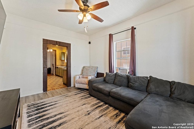 living area with light wood finished floors, ceiling fan, and a textured ceiling