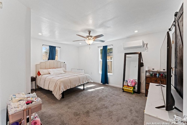 bedroom featuring a barn door, a textured ceiling, dark carpet, and an AC wall unit