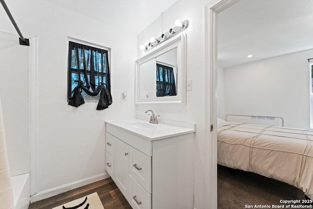 ensuite bathroom featuring baseboards, a textured wall, wood finished floors, ensuite bathroom, and vanity