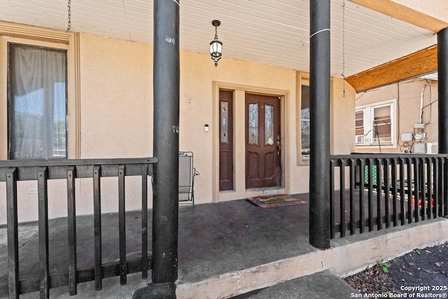 view of exterior entry with covered porch and stucco siding