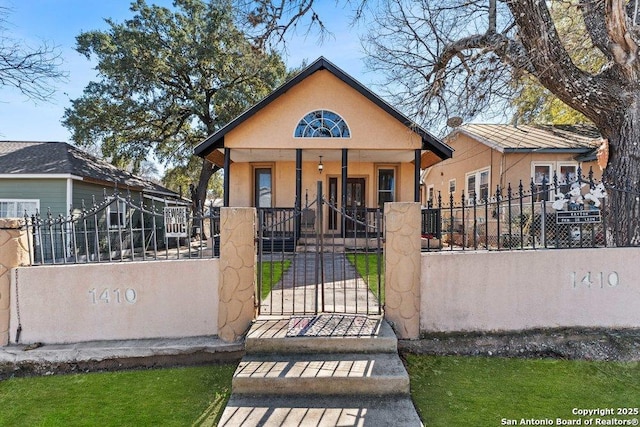 bungalow with a porch, a fenced front yard, a gate, and stucco siding