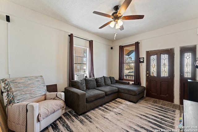 living area featuring a ceiling fan, a textured ceiling, and wood finished floors