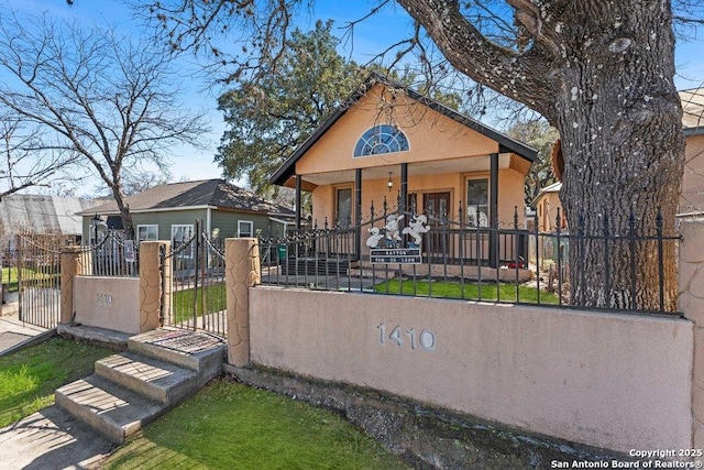 view of front of house with a fenced front yard, a gate, a porch, and stucco siding