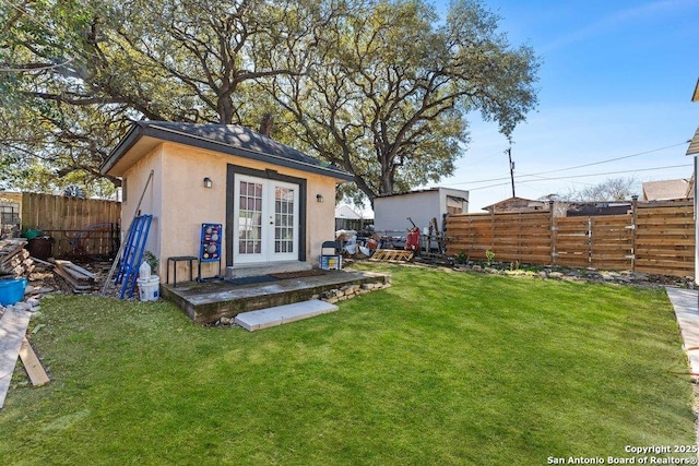 view of outdoor structure featuring an outbuilding, french doors, and a fenced backyard