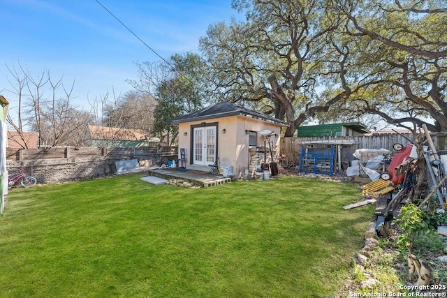 view of yard featuring french doors, an outdoor structure, and a fenced backyard