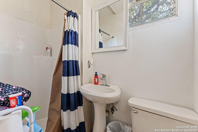 bathroom with toilet and a textured wall