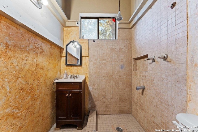 full bathroom featuring a tile shower, vanity, and toilet