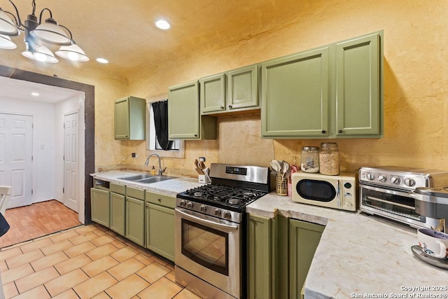 kitchen featuring gas stove, green cabinetry, and a sink