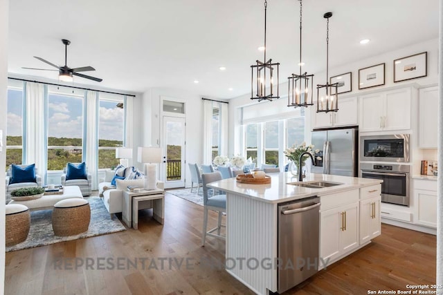 kitchen featuring appliances with stainless steel finishes, light countertops, an island with sink, and white cabinetry