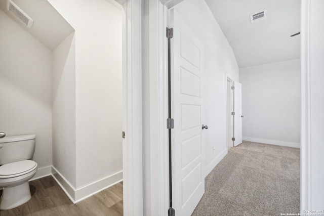 interior space with toilet, wood finished floors, visible vents, and baseboards