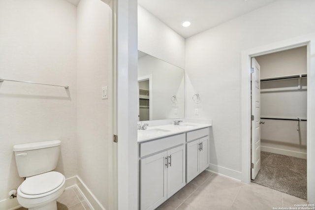 bathroom featuring a spacious closet, double vanity, tile patterned flooring, and a sink