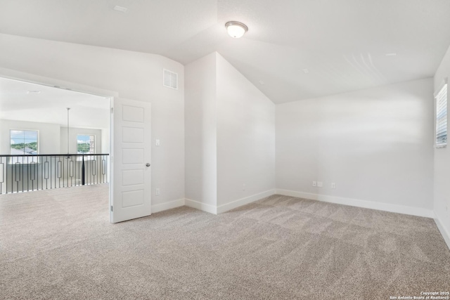 empty room with light carpet, lofted ceiling, visible vents, and baseboards