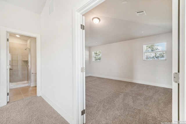 hallway with light carpet, visible vents, and baseboards