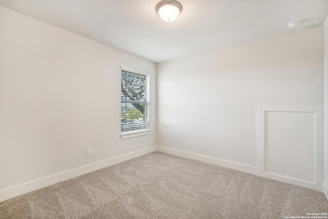 carpeted spare room featuring baseboards