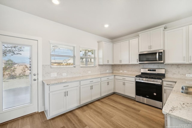 kitchen with appliances with stainless steel finishes, white cabinets, and decorative backsplash