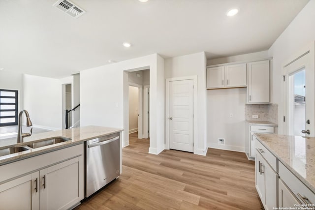 kitchen featuring visible vents, white cabinets, light stone countertops, stainless steel dishwasher, and a sink