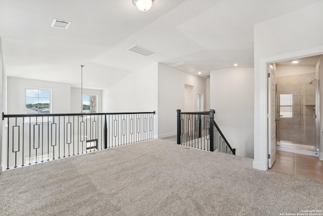 empty room featuring carpet, visible vents, and vaulted ceiling