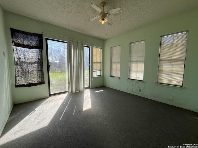 unfurnished room with a textured ceiling, a sunroom, carpet, and a ceiling fan