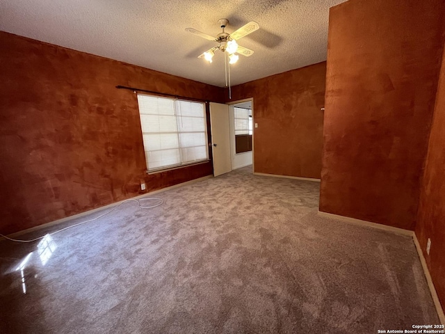 spare room with carpet, ceiling fan, a textured ceiling, and baseboards