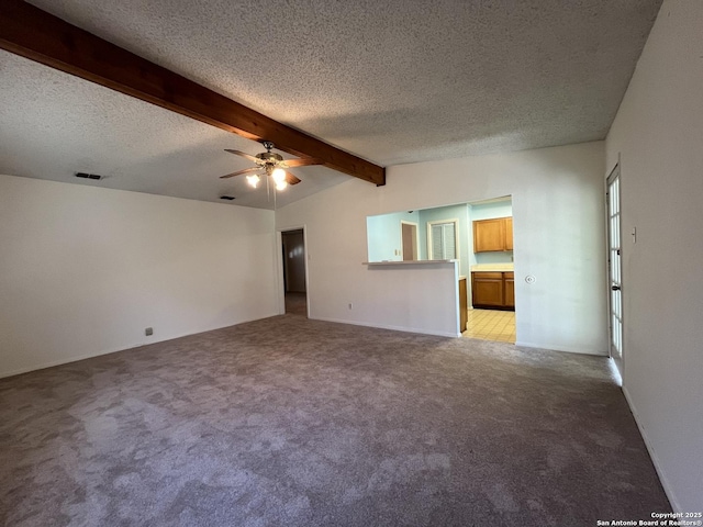 spare room with vaulted ceiling with beams, ceiling fan, a textured ceiling, light colored carpet, and visible vents