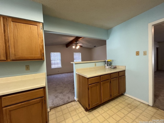 kitchen featuring light carpet, brown cabinetry, ceiling fan, a peninsula, and light countertops