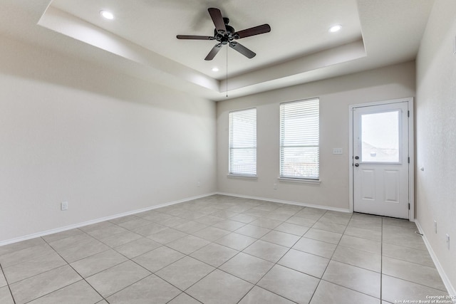 unfurnished room featuring recessed lighting, baseboards, ceiling fan, a tray ceiling, and light tile patterned flooring