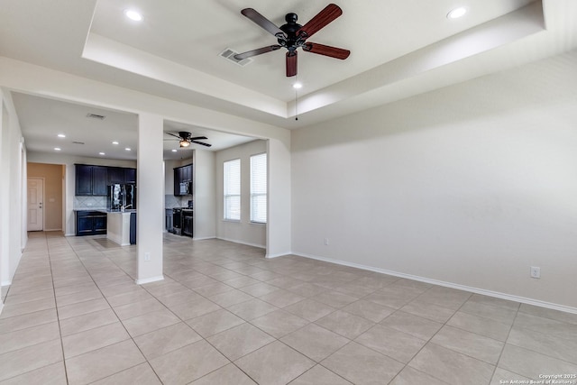 empty room with light tile patterned floors, visible vents, a tray ceiling, and recessed lighting