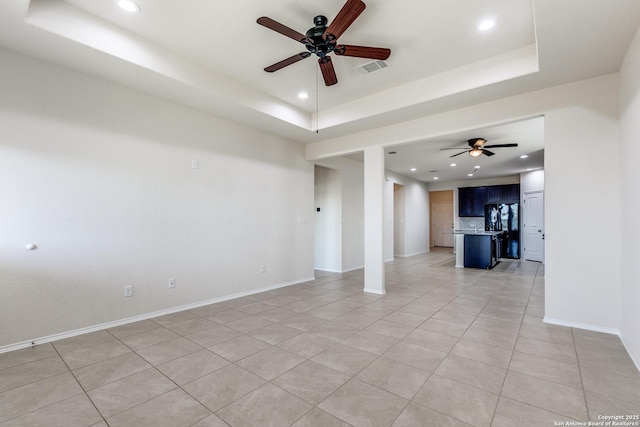 empty room with light tile patterned floors, a tray ceiling, baseboards, and recessed lighting