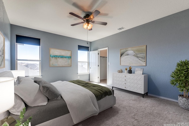 bedroom with a spacious closet, multiple windows, carpet, and visible vents