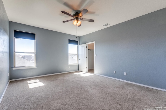 unfurnished bedroom with carpet floors, a spacious closet, visible vents, and baseboards