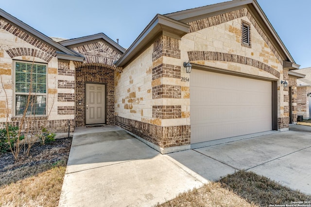 property entrance with brick siding, driveway, and an attached garage