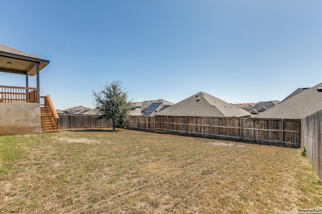 view of yard with a fenced backyard and stairway