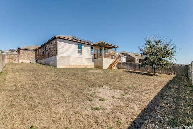 back of property featuring a fenced backyard, a lawn, stairway, and solar panels