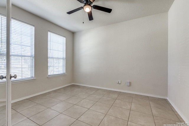 spare room featuring baseboards, a ceiling fan, and light tile patterned flooring