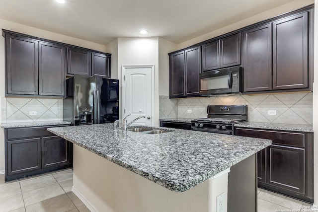 kitchen with light tile patterned floors, black appliances, stone counters, and a sink