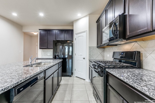 kitchen with light stone countertops, light tile patterned flooring, black appliances, a sink, and recessed lighting