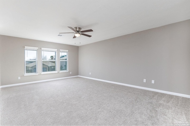 carpeted spare room with ceiling fan, visible vents, and baseboards