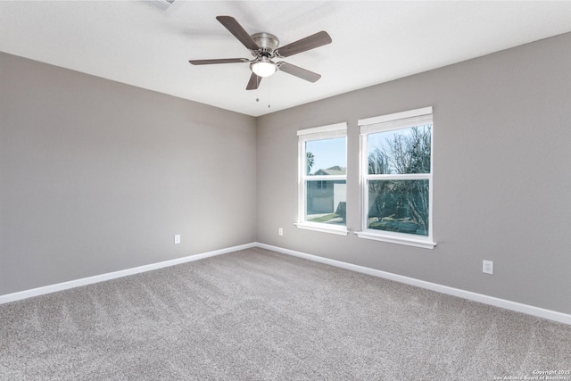 carpeted spare room with a ceiling fan and baseboards