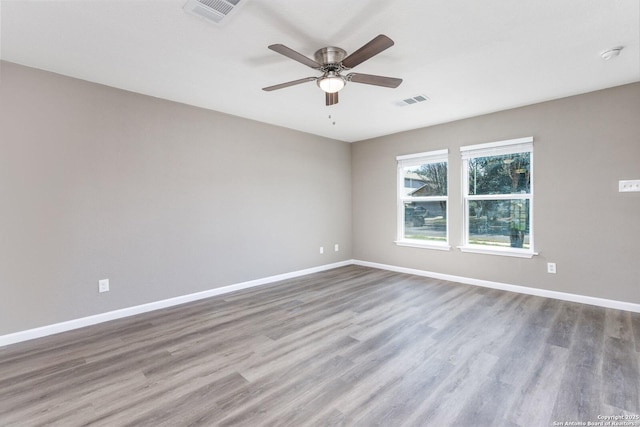 spare room with baseboards, visible vents, and wood finished floors