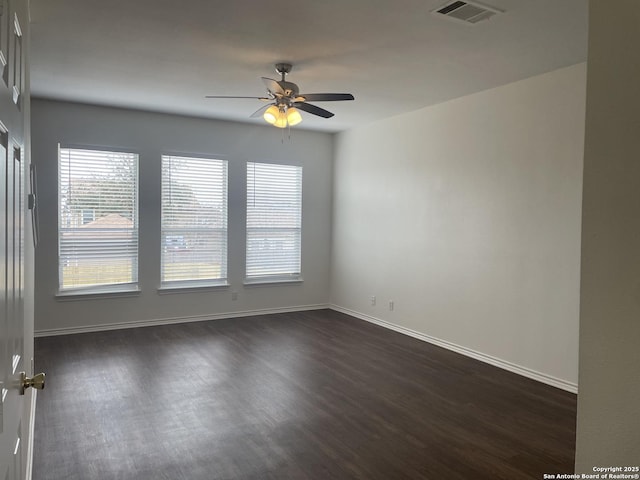 empty room with dark wood-style floors, baseboards, visible vents, and ceiling fan