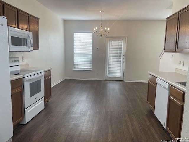 kitchen featuring a chandelier, white appliances, dark wood-style flooring, baseboards, and light countertops