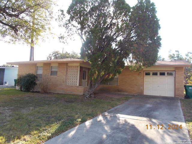 view of front of property with an attached garage, brick siding, driveway, and a front lawn