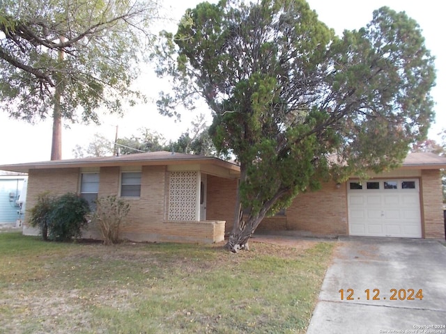 view of front of house featuring a front yard, concrete driveway, brick siding, and an attached garage