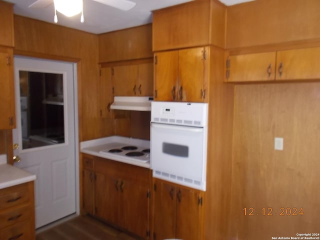 kitchen with brown cabinetry, white appliances, light countertops, and under cabinet range hood