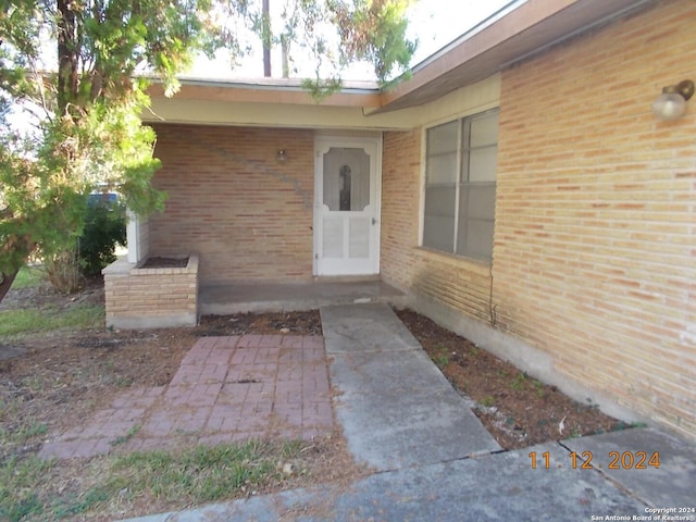 view of exterior entry featuring a patio and brick siding